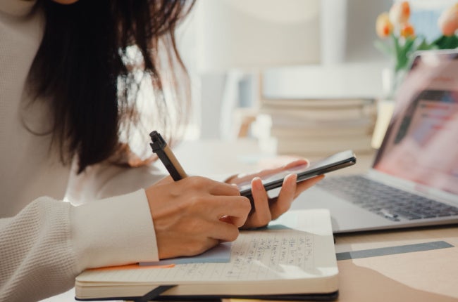 woman planning on cellphone laptop and agenda